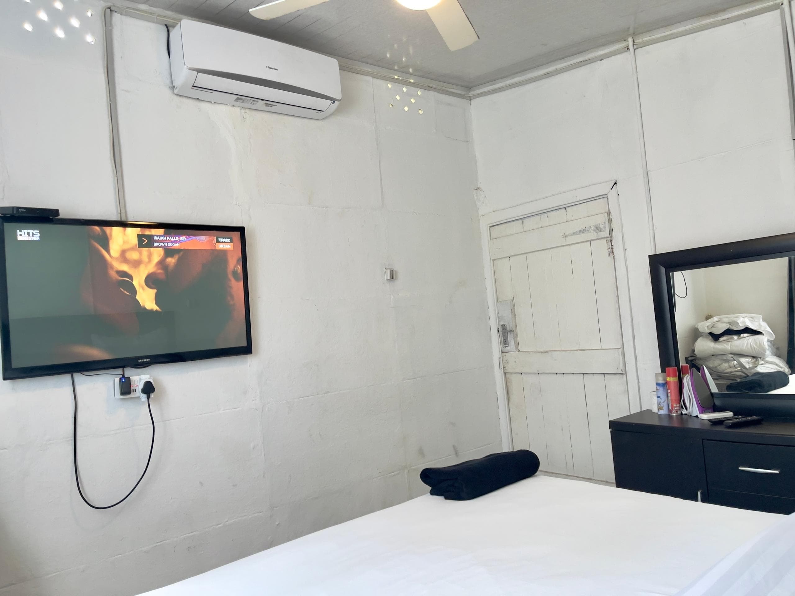 Majestic Haven — Bedroom with wall-mounted TV, AC, and ceiling fan